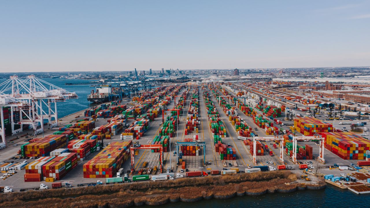 Crafting Captivating Headlines: Your awesome post title goes here Drone view of river embankment with various bright cargo containers near steel lifting cranes under cloudless sky